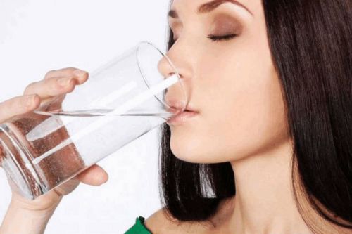 Женщина пьет воду из стакана